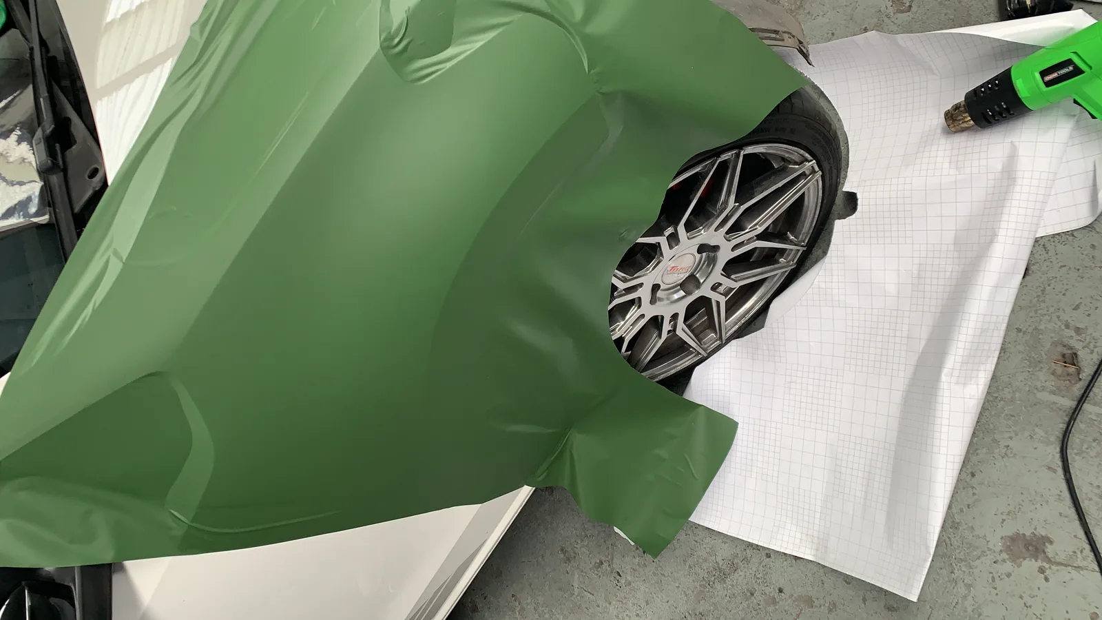 Technicien posant un film de covering sur un panneau de carrosserie
