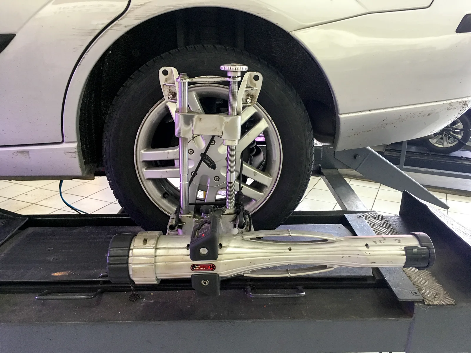 Voiture Ford Focus sur un pont élévateur avec des cibles de mesure fixées aux quatre roues pour le contrôle du parallélisme