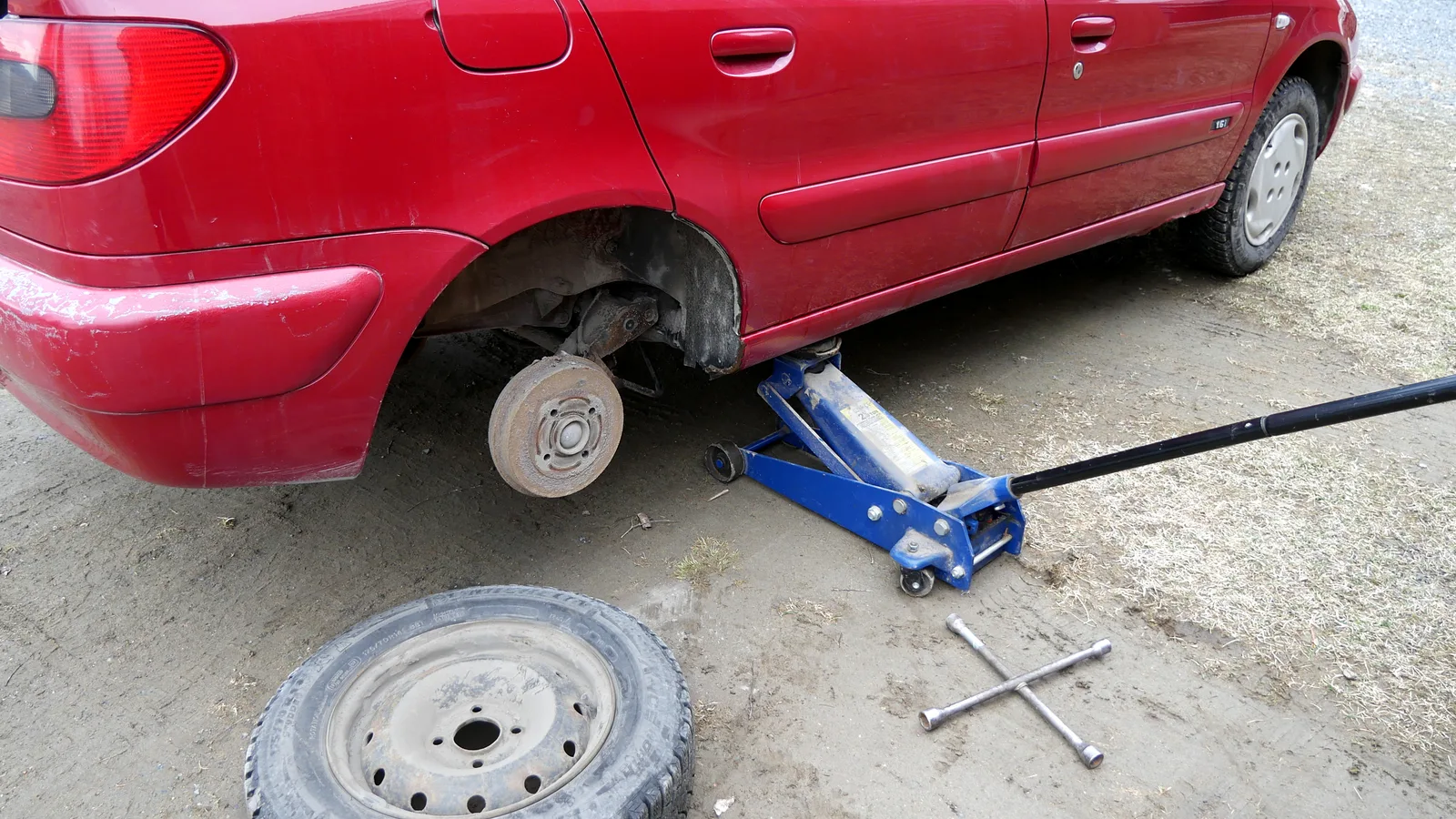 Changement de roue sur une voiture à l'aide d'une clé, au bord de la route