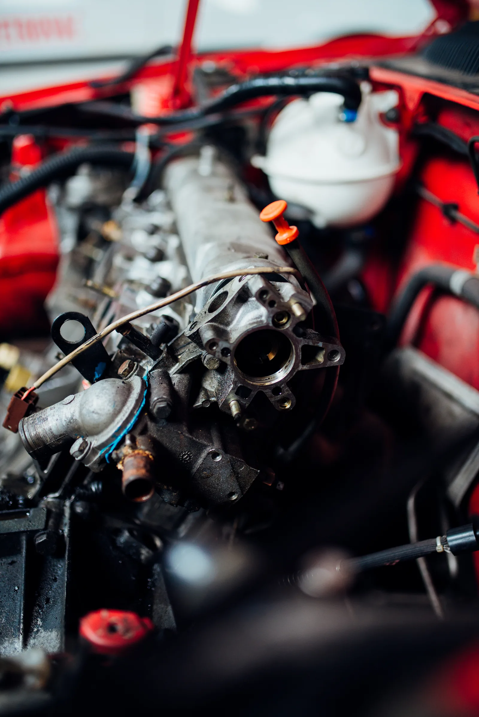 Mécanicien inspectant le moteur d'une voiture rouge dans un garage