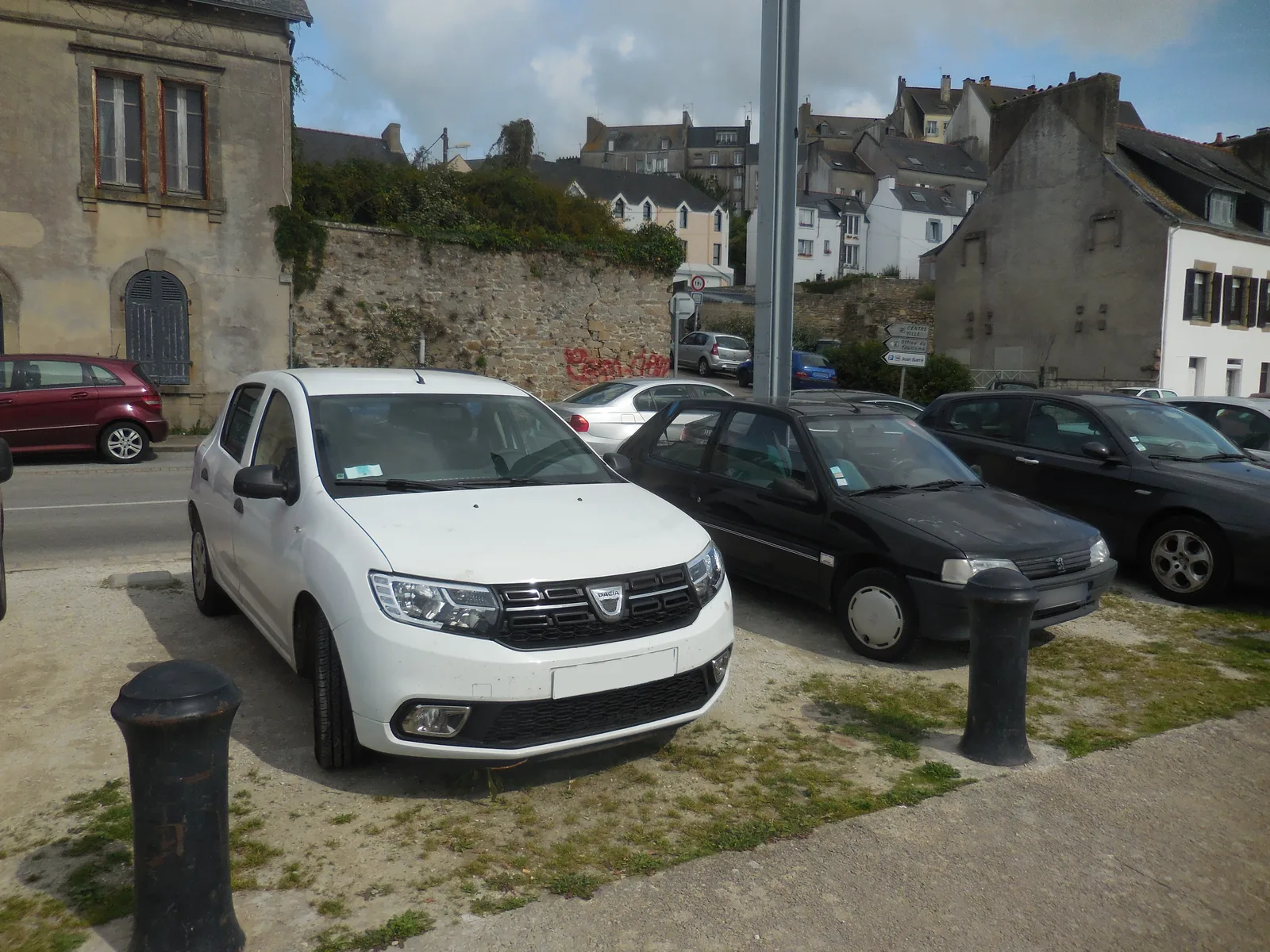Dacia Sandero II blanche garée en ville, citadine d'occasion économique à moins de 10 000 euros