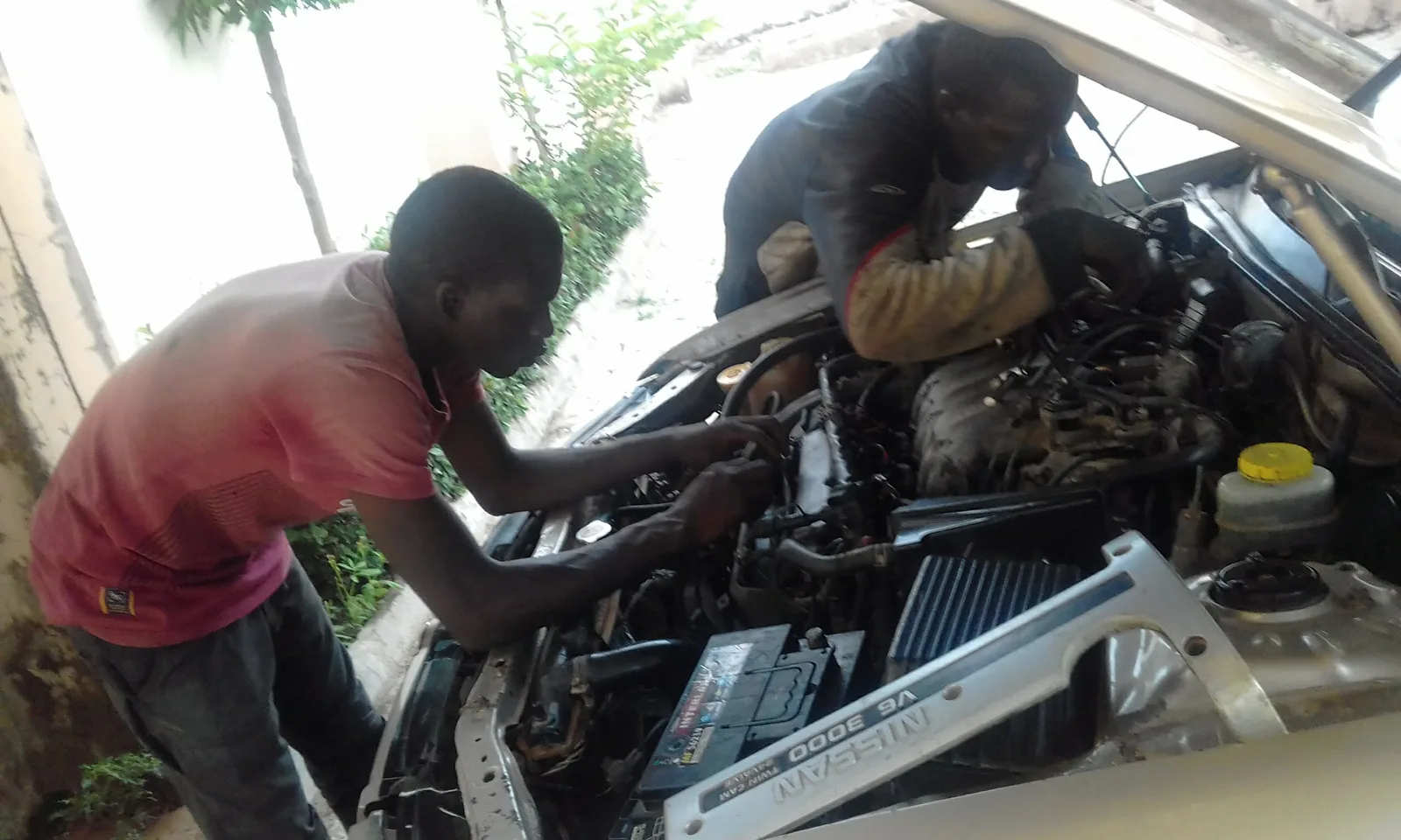 Mécaniciens qui travaillent sur le moteur d'une voiture, capot ouvert